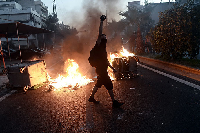 A protestor raises his fist as anti-fascist demonstrators clash with riot police in Athens on September 18, 2013, after a leftist musician was murdered by a suspected neo-Nazi. (AFP Photo / Aris Messinis)