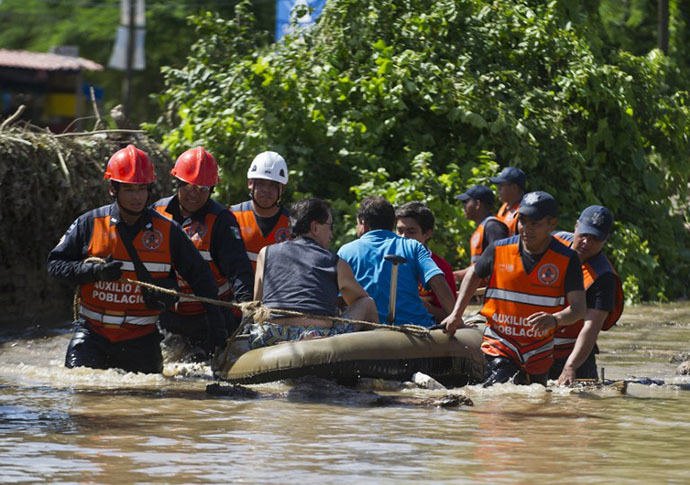 Rescued people are taken to safety by Mexican Federal Police officers on an inflatable dinghy in a flooded street of Acapulco, state of Guerrero, Mexico, on September 18, 2013 as heavy rains hit the country. (AFP Photo / Ronaldo Schemidt)