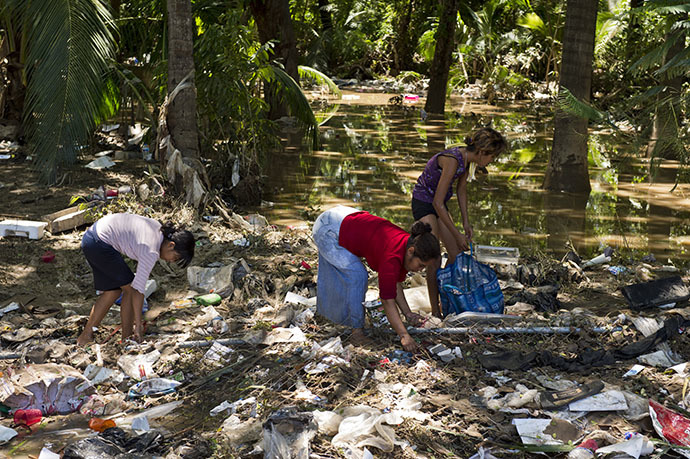 Residents search for food amid the debris in a flooded street of Acapulco, state of Guerrero, Mexico, on September 18, 2013 as heavy rains hit the country. (AFP Photo / Ronaldo Schemidt)