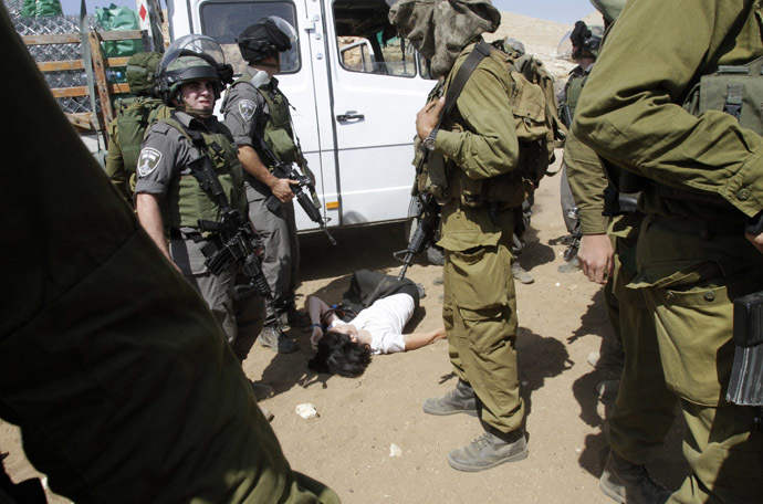 French diplomat Marion Castaing lays on the ground after Israeli soldiers carried her out of her truck containing emergency aid, in the West Bank herding community of Khirbet al-Makhul, in the Jordan Valley September 20, 2013. (Reuters/Abed Omar Qusini)
