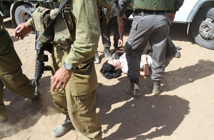 French diplomat Marion Fesneau-Castaing (C) lays on the ground after she was dragged out by Israeli soldiers from a truck loaded with supplies on September 20, 2013 on a road leading to the West Bank village of Khirbet al-Makhul. (AFP Photo)
