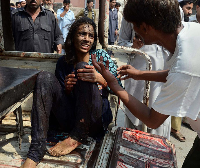 A Pakistani man helps an injured Christian woman on her arrival at the hospital after two suicide bomb attacks on a Church in Peshawar on September 22, 2013. (AFP Photo / A. Majeed)