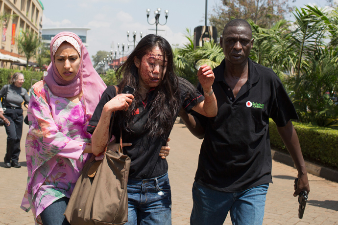 An injured woman (C) is helped out of the Westgate Shopping Centre where gunmen went on a shooting spree, in Nairobi September 21, 2013 (Reuters / Siegfried Modola)