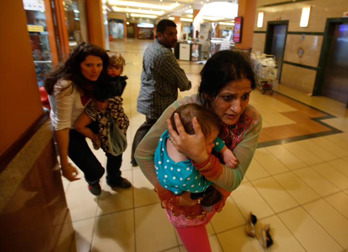 Women carrying children run for safety as armed police hunt gunmen who went on a shooting spree in Westgate shopping centre in Nairobi September 21, 2013 (Reuters / Goran Tomasevic)