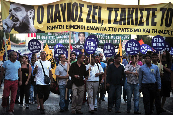 Protesters hold on September 25, 2013 a banner featuring a picture of the murdered anti-fascist musician, 34-year-old musician Pavlos Fyssas, and reading: "Pavlos lives, crack the fascists", during a massive demonstration in Athens heading toward the offices of the neo-Nazi party Golden Dawn (AFP Photo)