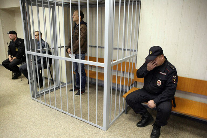 A handout picture taken late on September 26, 2013, and provided by Greenpeace International shows Greenpeace International contracted freelance photographer Denis Sinyakov sitting in a defendant cage in a court in the northern Russian city of Murmansk. (AFP Photo / Igor Podgorny)