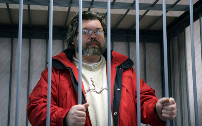 A handout picture taken late on September 26, 2013, and provided by Greenpeace International shows Greenpeace International expert Roman Dolgov standing in a defendant cage in a court in the northern Russian city of Murmansk. (AFP Photo / Igor Podgorny)