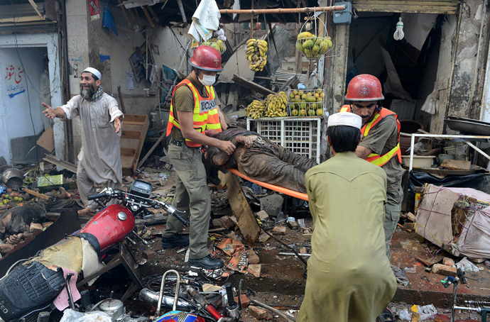 Pakistani volunteers carry a blast victim at the site of a bomb explosion in the busy Kissa Khwani market in Peshawar on September 29, 2013 (AFP Photo / A. Majeed) 