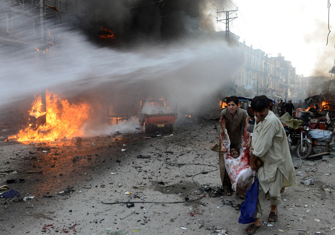 Pakistani men carry an injured blast victim at the site of a bomb explosion in the busy Kissa Khwani market in Peshawar on September 29, 2013 (AFP Photo / Hasham Ahmed) 
