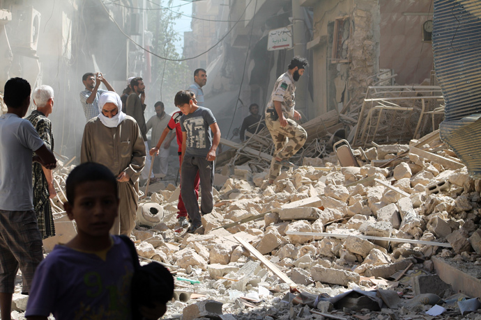 Residents of Syria's eastern town of Deir Ezzor walk past the debris of a building reportedly hit by a missile (AFP Photo / Ahmad Aboud) 