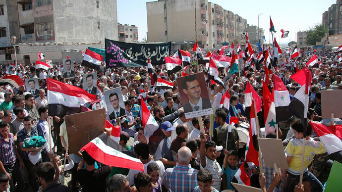 Syrian demonstrators waving their national flag and pictures of President Bashar al-Assad during a march near the central city of Homs, in support of the country's army.(AFP Photo / SANA)