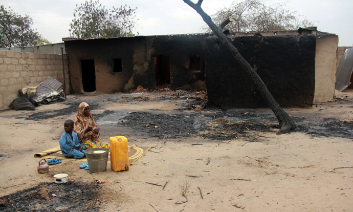 Children sit in front of a burnt house in the remote northeast town of Baga on April 21, 2013 after two days of clashes between officers of the Joint Task Force and members of the Islamist sect Boko Haram on April 19 in the town near Lake Chad, 200 kms north of Maiduguri, in Borno State. (AFP Photo)