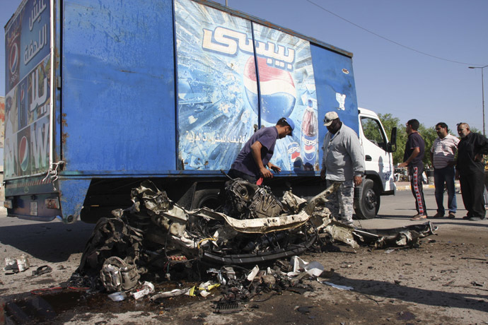 Residents inspect the mangled remains of a vehicle at the site of a car bomb attack in Baghdad's Sadr City, September 30, 2013. (Reuters/Wissm al-Okili)
