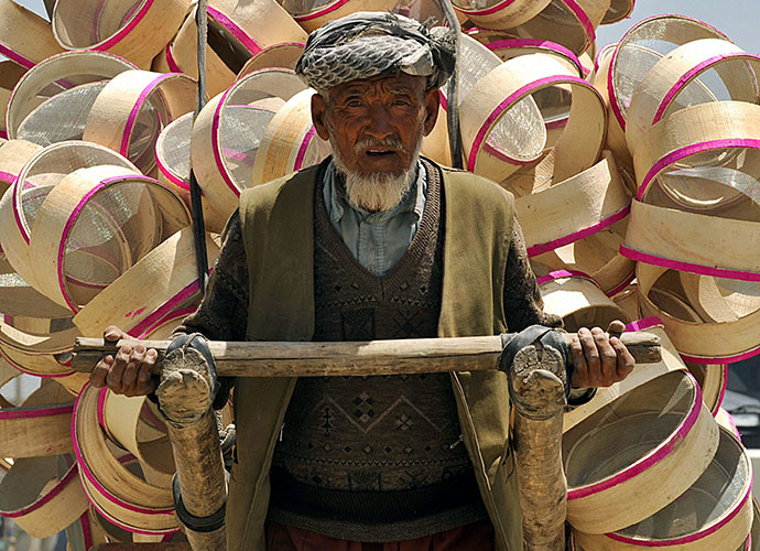 An elderly Afghan man pulls a handcart loaded with hand-made sieves (AFP Photo / Shah Marai)