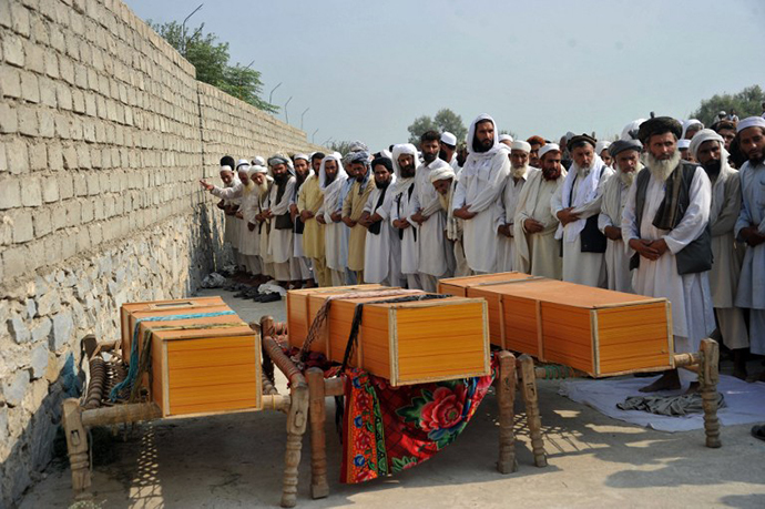 Afghan men pray alongside the coffins of civilians, allegedly killed in a NATO air strike, on the outskirts of Jalalabad in Nangarhar province on October 5, 2013. (AFP Photo / Noorullah Shirzada)