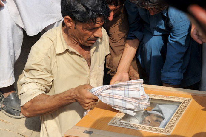 An Afghan man looks at the face of relative in a coffin, allegedly killed in a NATO air strike, on the outskirts of Jalalabad in Nangarhar province on October 5, 2013. (AFP Photo / Noorullah Shirzada)