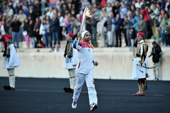 The last torch bearer, Greek figure skater Panagiotis Markouizos (C), brings the Olympic flame on October 5, 2013 into the Panathenaic stadium in Athens. (AFP Photo / Louisa Gouliamaki)