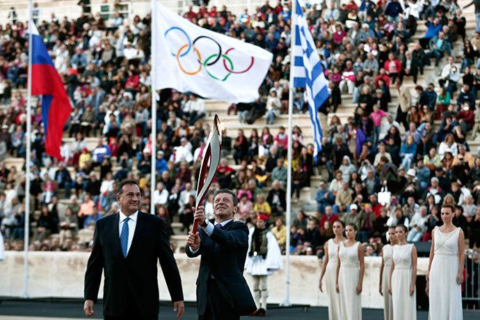 Russia's Deputy Prime Minister Dmitry Kozak (C) raises an Olympic torch for the Sochi 2014 Winter Games next to President of the Greek Olympic Committee Spyros Kapralos during a handover ceremony at the Panathenean stadium in Athens October 5, 2013.(Reuters / Yorgos Karahalis)