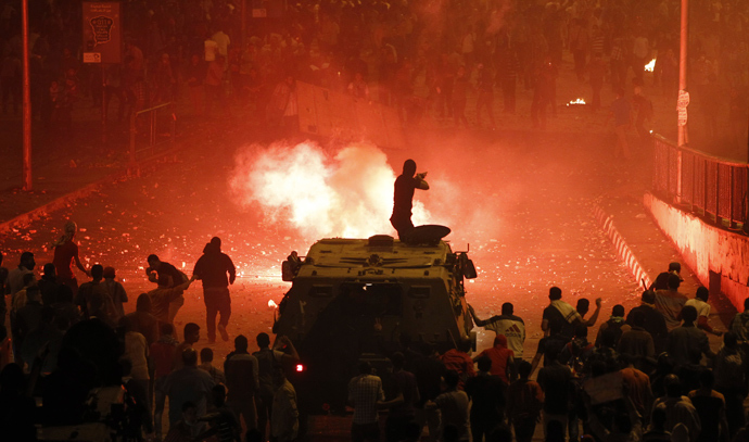 A riot police officer, on a armoured personnel carrier surrounded by anti-Mursi protesters (foreground), fires rubber bullets at members of the Muslim Brotherhood and supporters of ousted Egyptian President Mohamed Mursi along a road at Ramsis square, which leads to Tahrir Square, during clashes at a celebration marking Egypt's 1973 war with Israel, in Cairo October 6, 2013 (Reuters / Amr Abdallah Dalsh)
