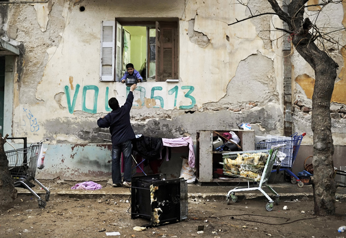 A migrant gives food donated by activists from a local soup kitchen to a boy, in a poor neighborhood in Athens (AFP Photo / Louisa Gouliamaki)