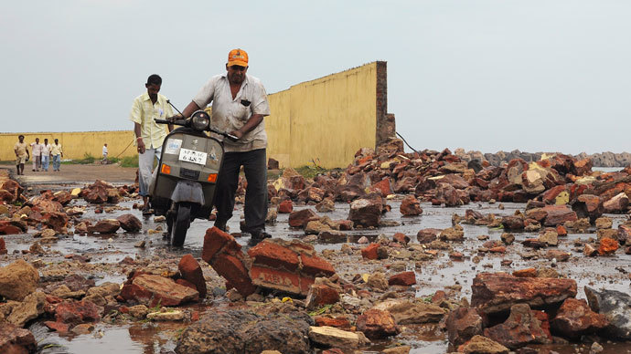 People walk among debris from a broken wall after it was damaged by a wave brought by Cyclone Phailin at a fishing harbour in Visakhapatnam district in the southern Indian state of Andhra Pradesh October 12, 2013. (Reuters / R Narendra)