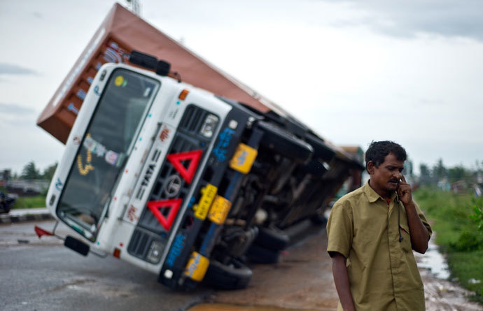 Indian truck driver Jairam Yadav speaks on his mobile phone after his truck carrying Toyota cars was overturned by strong wind on the National Highway linking Andhra Pradesh and Odisha on October 13, 2013.(AFP Photo / Manan Vatsyayana)