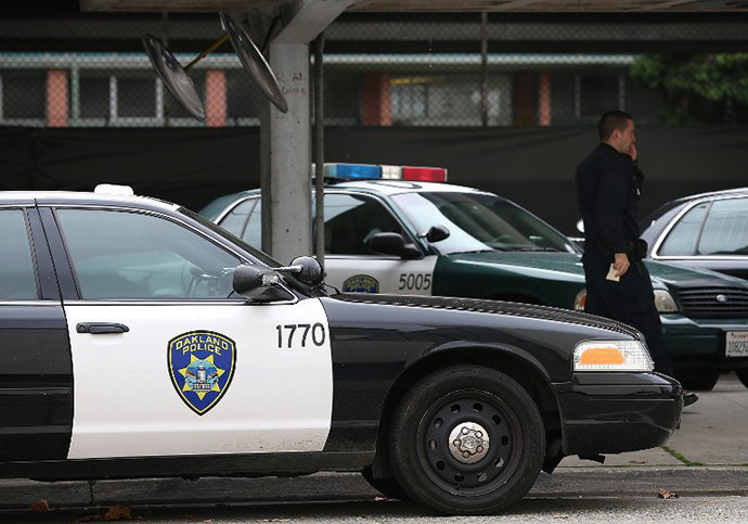 An Oakland Police officer walks by patrol cars at the Oakland Police headquarters (AFP Photo / Getty Images / Justin Sullivan)