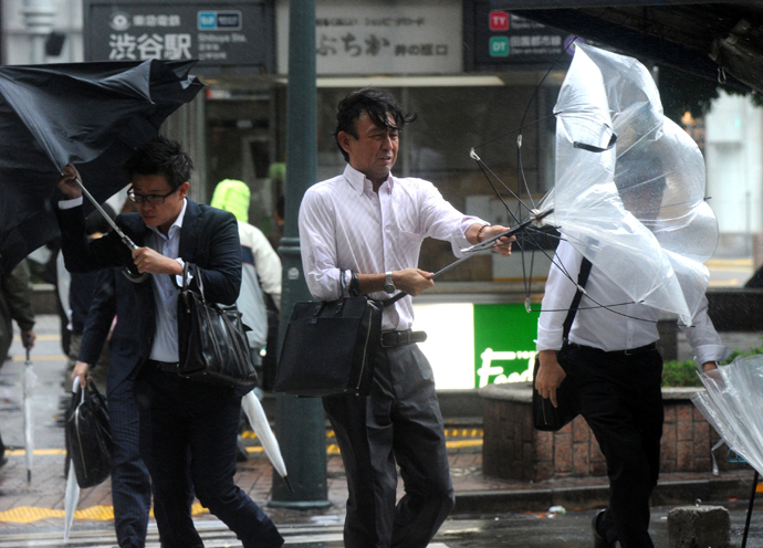 Japanese businessmen walk against strong wind and rain in Tokyo on October 16, 2013 (AFP Photo / Yoshikazu Tsuno)
