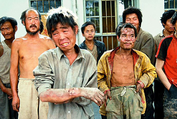 A group of rescued workers stand outside a police station after they were saved from a brick kiln in Linfen, northern China's Shanxi province 27 May 2007. Police said 14 June that they had rescued more than 200 people, including 29 children, who were working as "slaves" in brick kilns, in a shocking revelation of labour practices in booming China. (AFP Photo)