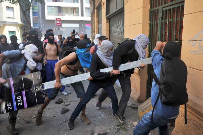 Demonstrators try to knock down the door of a house where there are policemen inside during a protest of sutudents demanding to Chilean President Sebastian Pinera's government to improve the public education quality, in Santiago, on October 17, 2013. (AFP Photo/Hector Retamal)