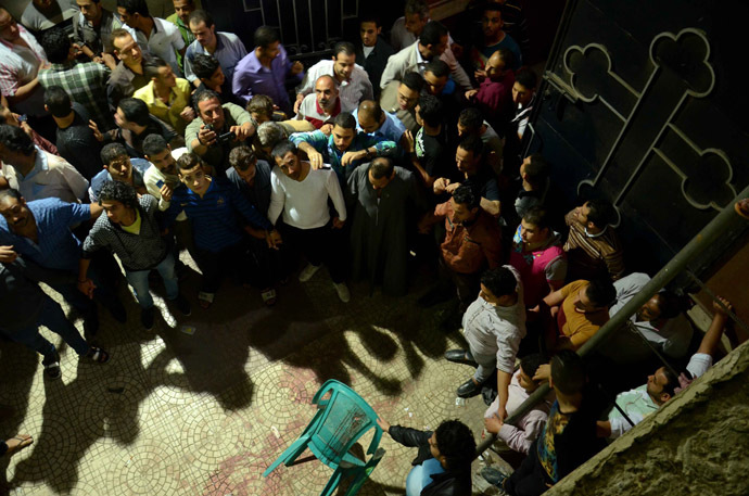 Egyptians gather around blood stains at the entrance of the Virgin Mary Coptic Christian church in Cairo after gunmen on a motorbike shot dead three people late on October 20, 2013, including an eight-year-old girl, in a shooting attack on a group standing outside the church in the Egyptian capital's Al-Warak neighbourhood following a wedding ceremony. (AFP Photo)