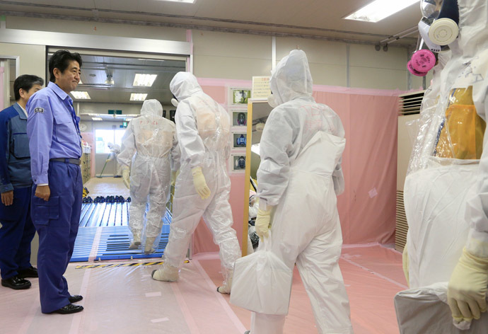 Japanese Prime Minister Shinzo Abe (L) sees off workers leaving for a patrol of tanks containing radioactive water after greeting them at the emergency operation center of the Tokyo Electric Power Co. (AFP Photo/Japan Pooll)