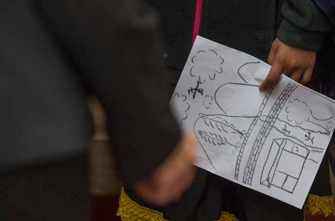 Nabila Rehman, 9, who was injured by a US drone strike in Pakistan, holds a hand drawn picture of the strike during a press conference on Capitol Hill in Washington, DC, October 29, 2013 (AFP Photo / Jim Watson