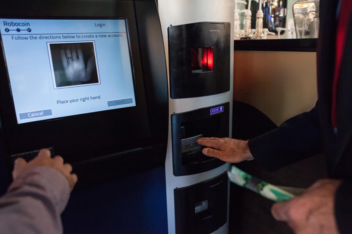 A user is instructed on how to scan his palm using scanning identification to ensure that a single user cannot exchange more than $1,000 in a single day day on the world's first bitcoin ATM at Waves Coffee House on October 29, 2013 in Vancouver, British Columbia (AFP Photo / David Ryder)