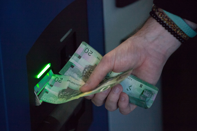 A user inserts Canadian currency into the world's first bitcoin ATM in exchange for bitcoins ATM at Waves Coffee House on October 29, 2013 in Vancouver, British Columbia, Canada (AFP Photo / David Ryder)