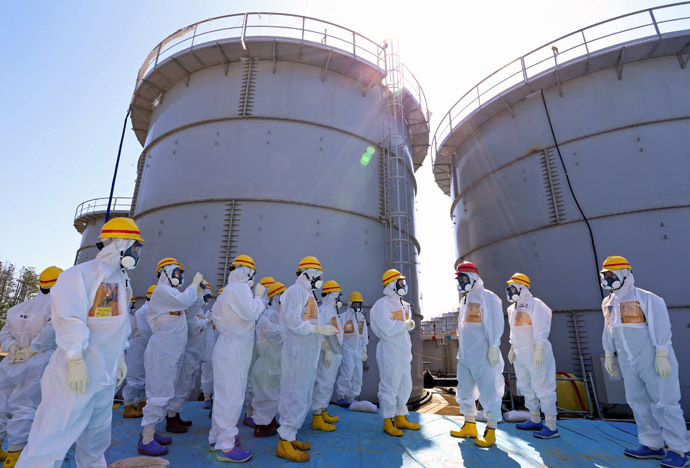 Japan's Prime Minister Shinzo Abe (in red helmet), wearing protective suit and mask, is briefed about tanks containing radioactive water by Fukushima Daiichi nuclear power plant chief Akira Ono (4th R) during his inspection tour to the Tokyo Electric Power Co. (TEPCO)'s tsunami-crippled Fukushima Daiichi nuclear power plant in Okuma, Fukushima Prefecture, September 19, 2013. (Reutes/Japan out) 