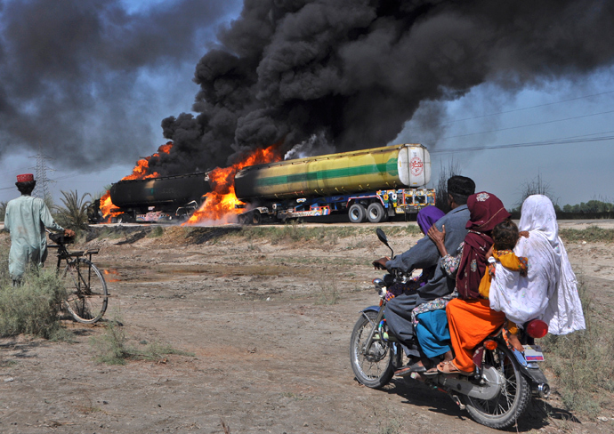 Residents on a motorbike look at burning fuel trucks attacked by gunmen on a highway near Shikarpur in Pakistan's Sindh province (Reuters / Nadeem Soomro)
