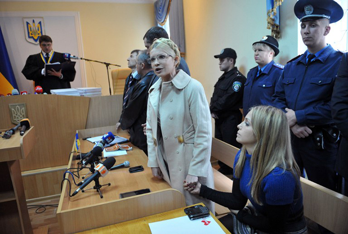 Yevgenia Carr (R) holds hands with her mother Yulia Tymoshenko who addresses Ukrainians while Rodion Kireyev, judge of Kiev Pechersky court reads a verdict to her during the sittings in Kiev on October 11, 2011. (AFP Photo / Sergei Supinsky)