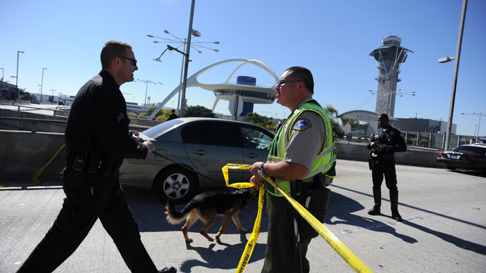A K-9 officer (L) crosses a crime tape line on November 1, 2013 after a gunman reportedly opened fire at a security checkpointin Los Angeles International Airport. (AFP Photo / Robyn Beck)