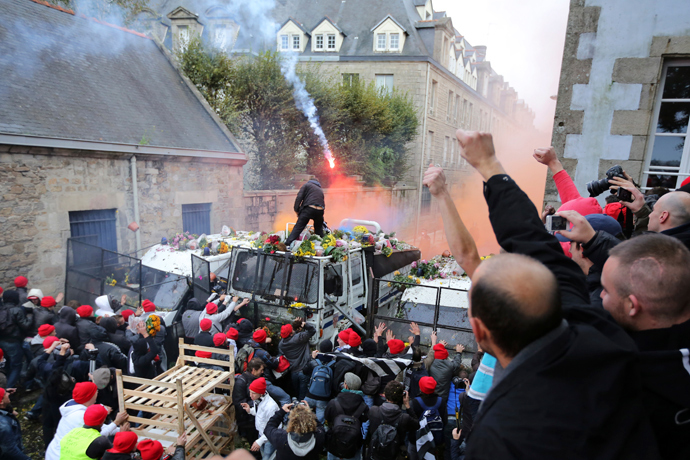 Protesters wearing red caps, the symbol of protest in Brittany, throw objects at a barricade held by French riot police during a demonstration to maintain jobs in Quimper, western France, November 2, 2013 (Reuters / Stephane Mahe)