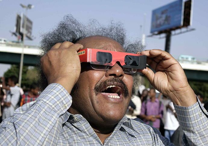 A Sudanese man reacts as he looks through tinted glasses towards the sun to watch a partial solar eclipse over the Sudanese capital Khartoum, on November 3, 2013. (AFP Photo / Ebrahim Hamid)