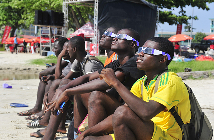 People look at a rare solar eclipse wearing special glasses, on November 3, 2013 in Libreville. (AFP Photo / Steve Jordan)