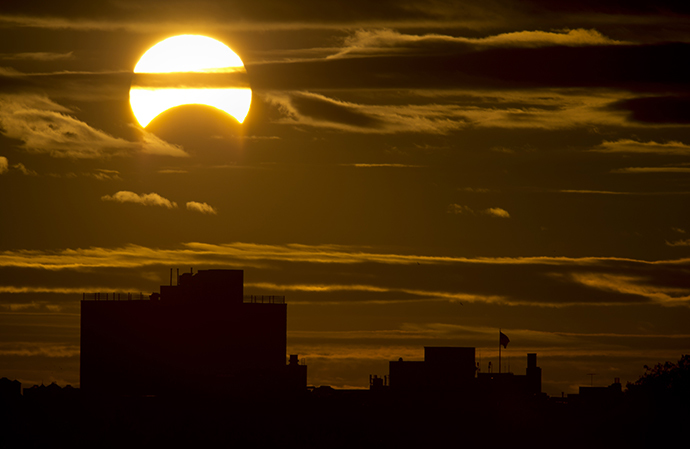 A partial Solar eclipse is seen just after sunrise over the Queens borough of New York across the East River on November 3, 2013 in New York. (AFP Photo / Stan Honda)