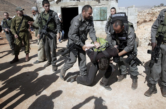 Israeli security detain a foreign activist as he and others, including Palestinians, try to stop the demolishion a small house (behind) belonging to a Palestinian family in Khirbit al-Tawil, in the northern West Bank on October 29, 2013, which was built with out a permit from Israel. (AFP Photo / Jaafar Ashtiyeh)