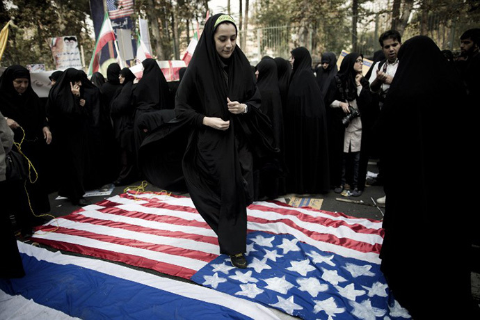 An Iranian woman steps on a US flag outside the former US embassy in Tehran on November 4, 2013, during a demonstration to mark the 34th anniversary of the 1979 US embassy takeover. (AFP Photo / Behrouz Mehri)