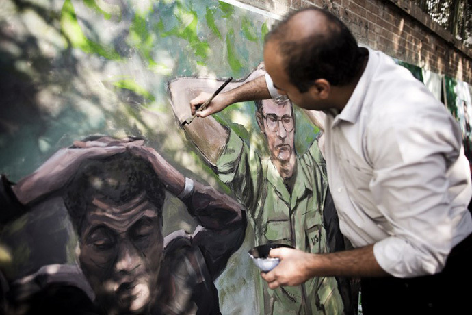 An Iranian man puts the final touches on his painting outside former US embassy in Tehran on November 4, 2013, depicting the US hostages after the seizing the US embassy in 1979, during a demonstration to mark the 34th anniversary of the 1979 US embassy takeover. (AFP Photo / Behrouz Mehri)