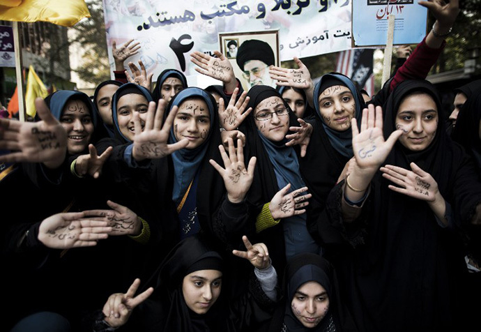 Iranian schoolgirls show their palms with anti-US slogans outside the former US diplomatic mission in Tehran during a demonstration on November 4, 2013 to mark the 34th anniversary of the 1979 US embassy takeover. (AFP Photo / Behrouz Mehri)