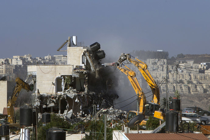 An Israeli municipality worker uses a mechanical shovel to demolish a house, belonging to a Palestinian family, that was built without municipal permission in the Arab east Jerusalem neighborhood of Beit Hanina on October 29, 2013. (AFP Photo)