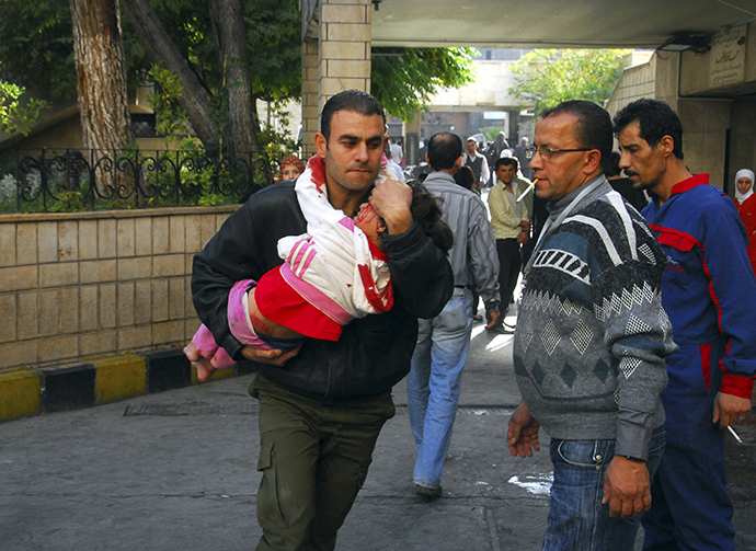 A man carries an injured child after a bomb explosion in front of the al-Hejaz train station in central Damascus November 6, 2013 in this picture provided by Syria's national news agency SANA. (AFP Photo)