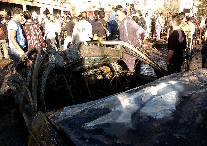 People gather around wreckage after a car bomb in Suweida city, November 6, 2013, in this handout picture released by Syria's national news agency SANA. (Reuters)